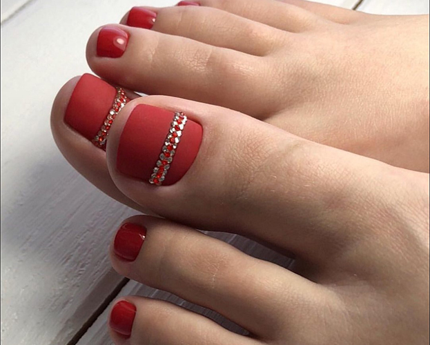 Pédicure rouge sur les pieds. Photo avec design, strass, motifs, frottements